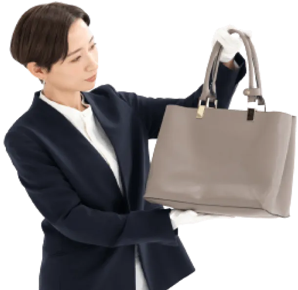 おうちで出張買取でバッグの買取金額を査定している女性